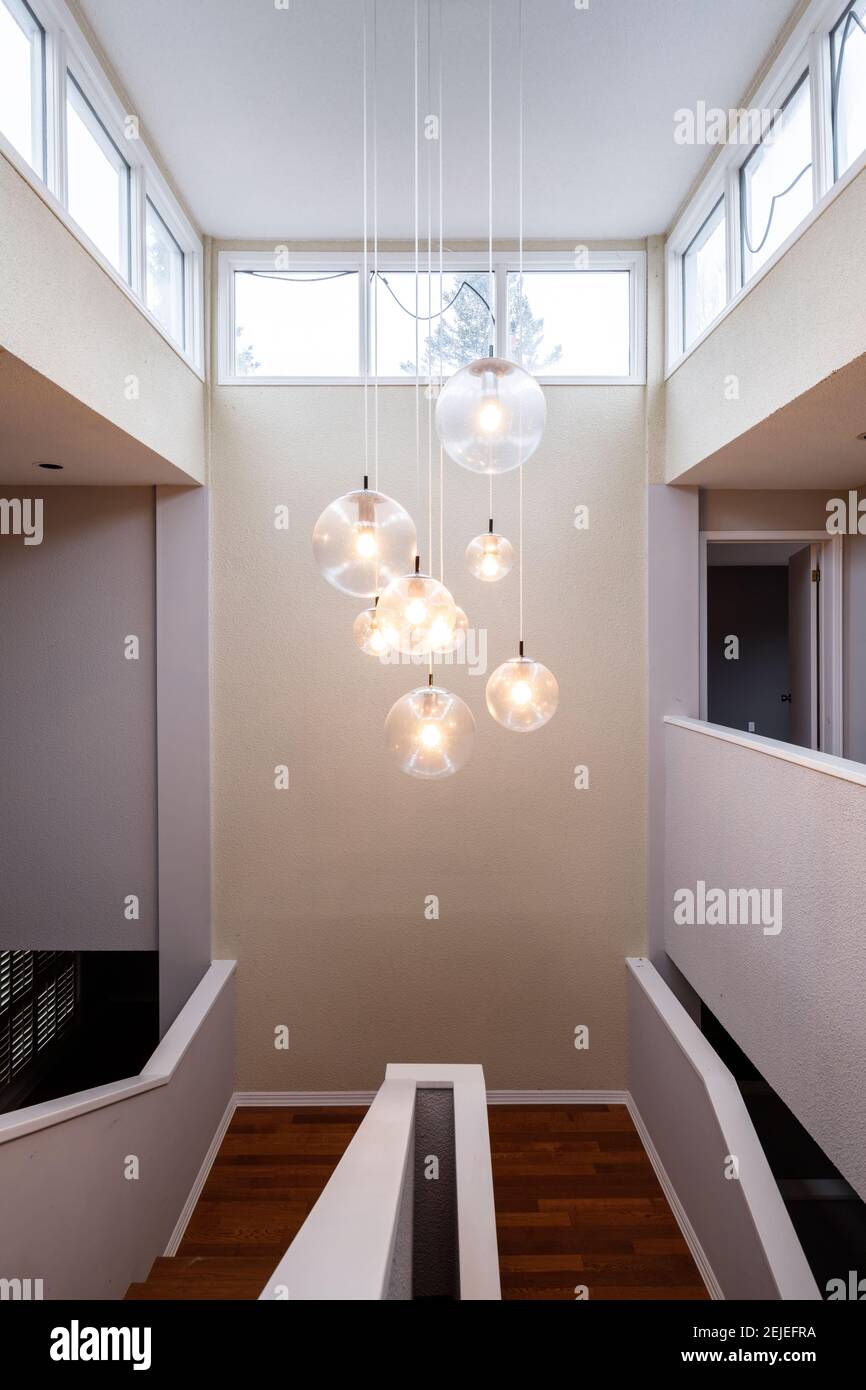 A contemporary chandelier hanging over a stairwell in a large home