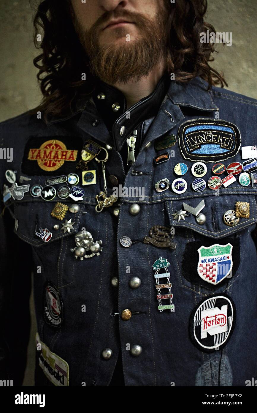 Portrait of a bearded Rocker with denim jeans vest with patches . Rocker Denim Jean Vest Jacket  Jeans .jacket with various badges Stock Photo