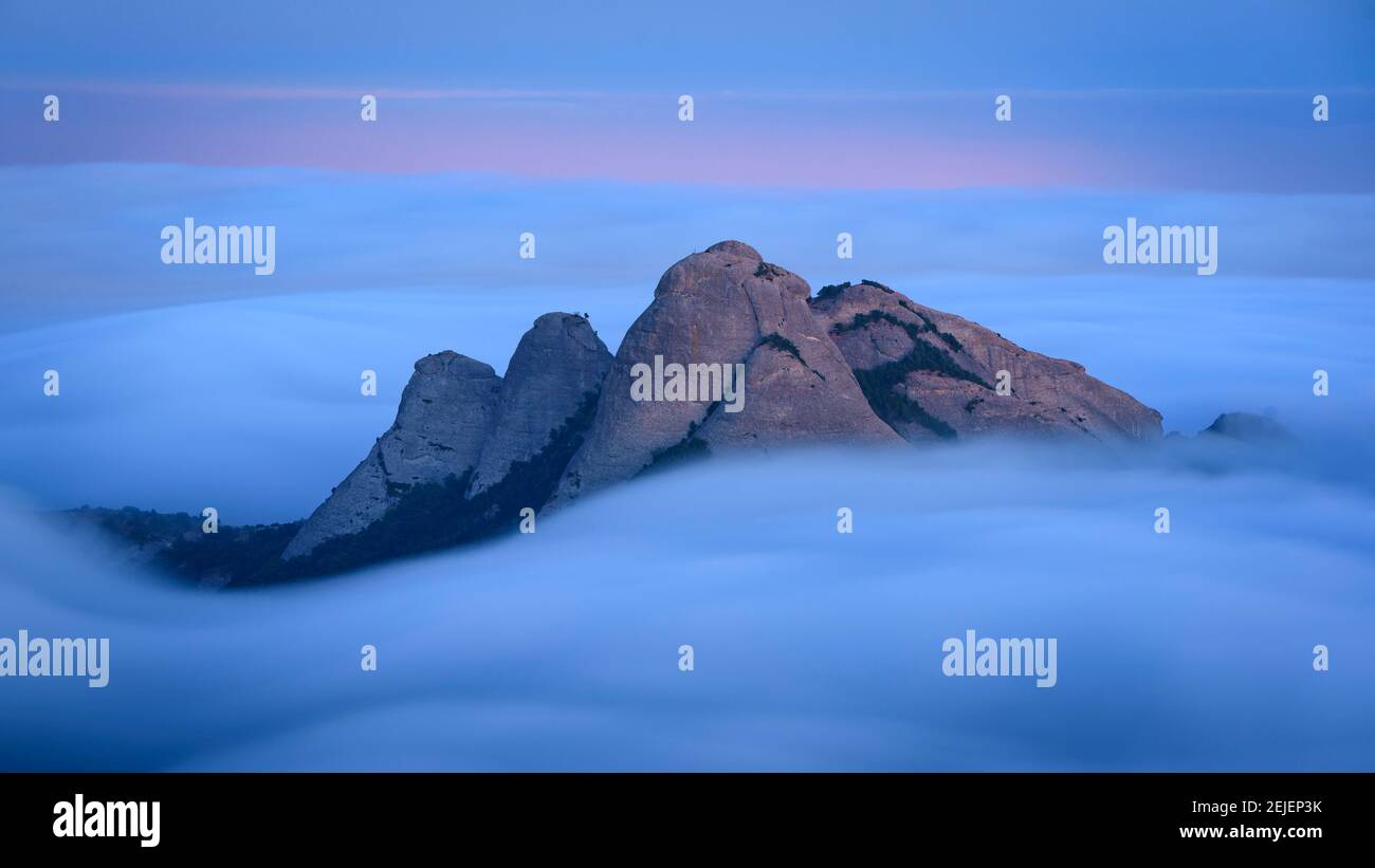 Blue hour at twilight in Montserrat with fog looking to the spires of Gorres and Magdalenes seen from the Sant Jeroni summit (Barcelona, Spain) Stock Photo