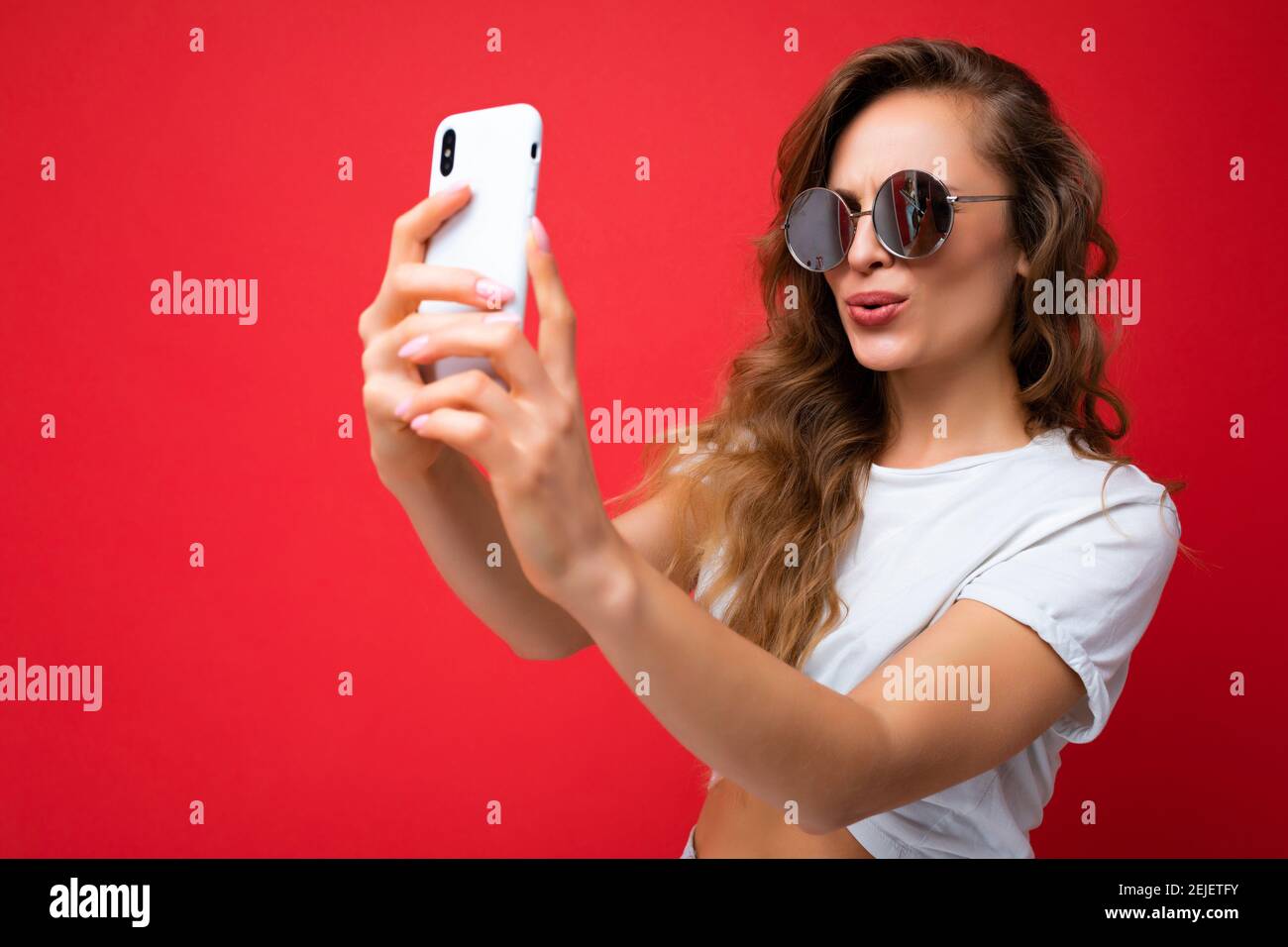 Closeup photo of beautiful young blonde woman holding mobile phone ...