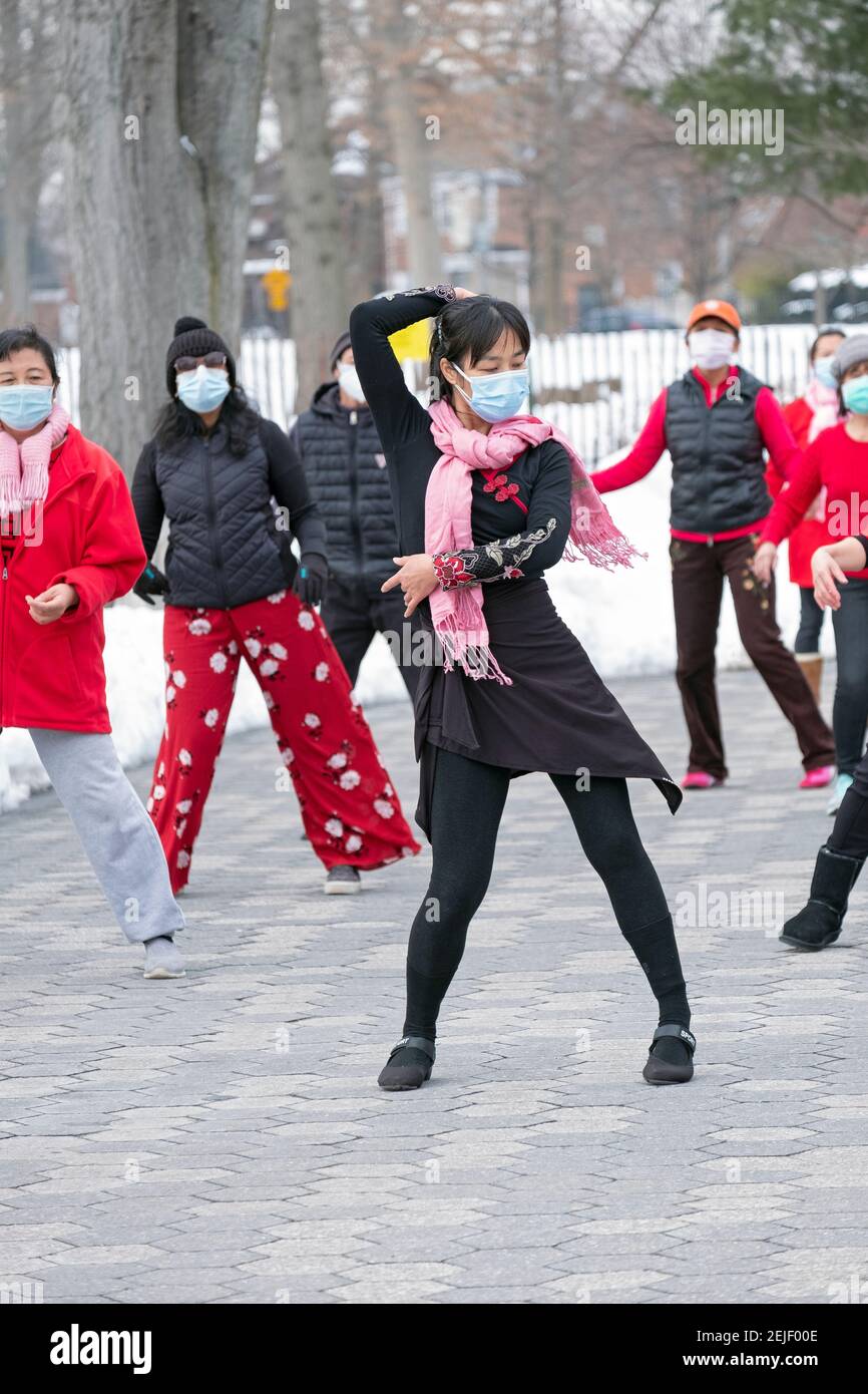 A slender graceful Chinese American woman leads a dance exercise class on a cold winter day. In a Flushing Queens, New York park. Stock Photo