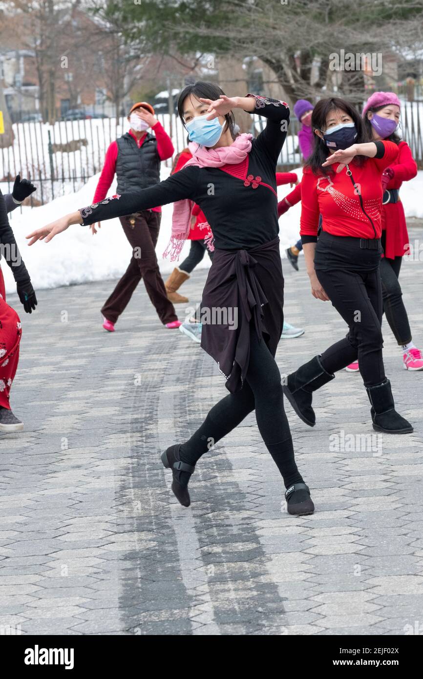 A slender graceful Chinese American woman leads a dance exercise class on a cold winter day. In a Flushing Queens, New York park. Stock Photo