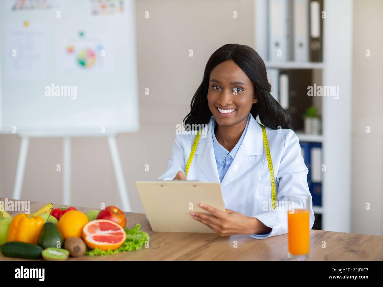 Young black nutritionist with clipboard creating plant based meal plan