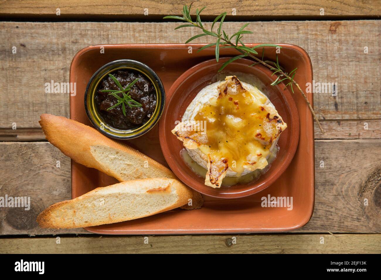French Camembert that has been baked in an oven with a truffle, garlic and honey sauce, served with toasted French bread and caramelised onion chutney Stock Photo