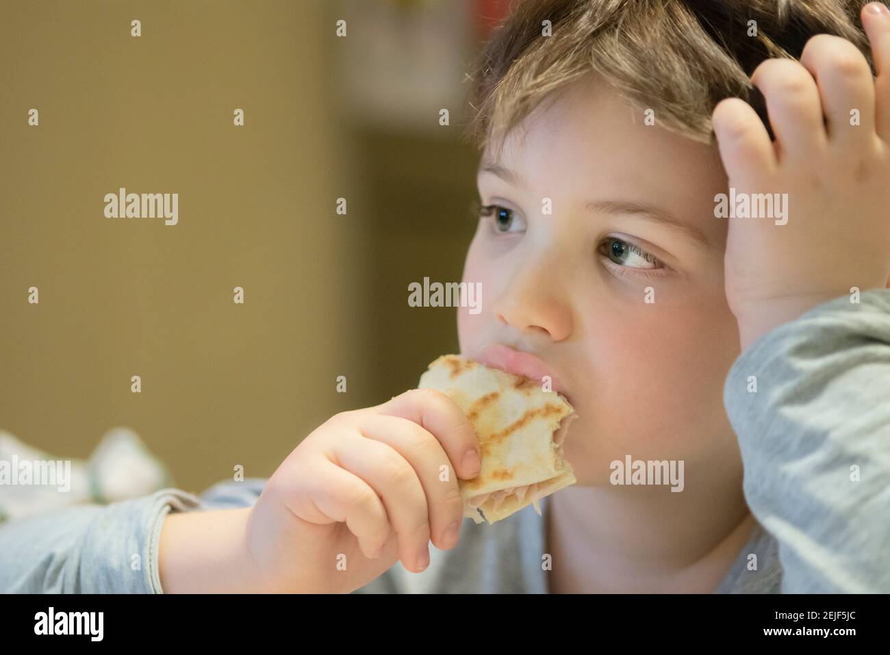 Boy Eating Piadina While Watching TV at Home Stock Photo