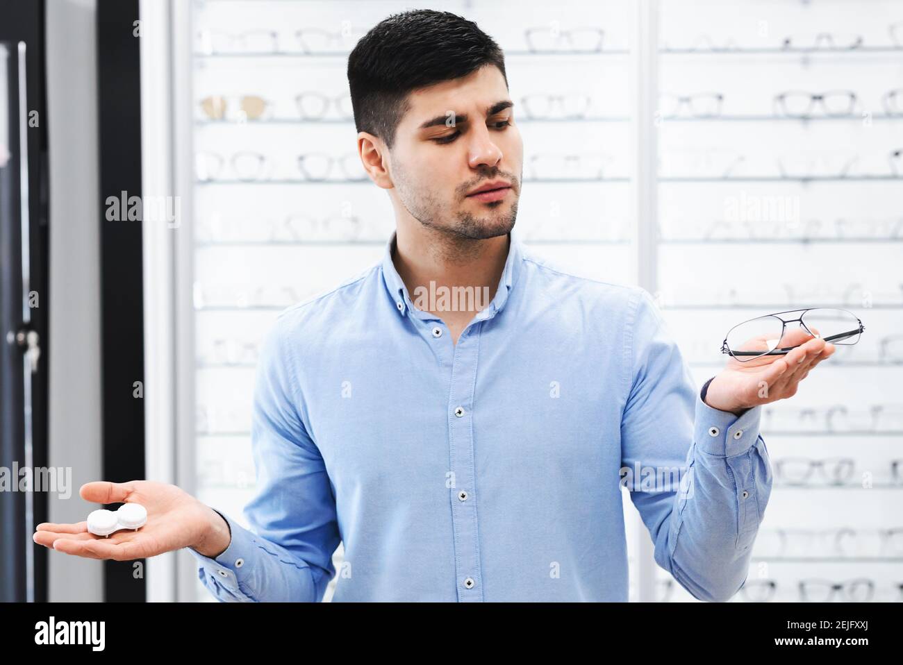 Thinking guy choosing between eyeglasses and contacts Stock Photo
