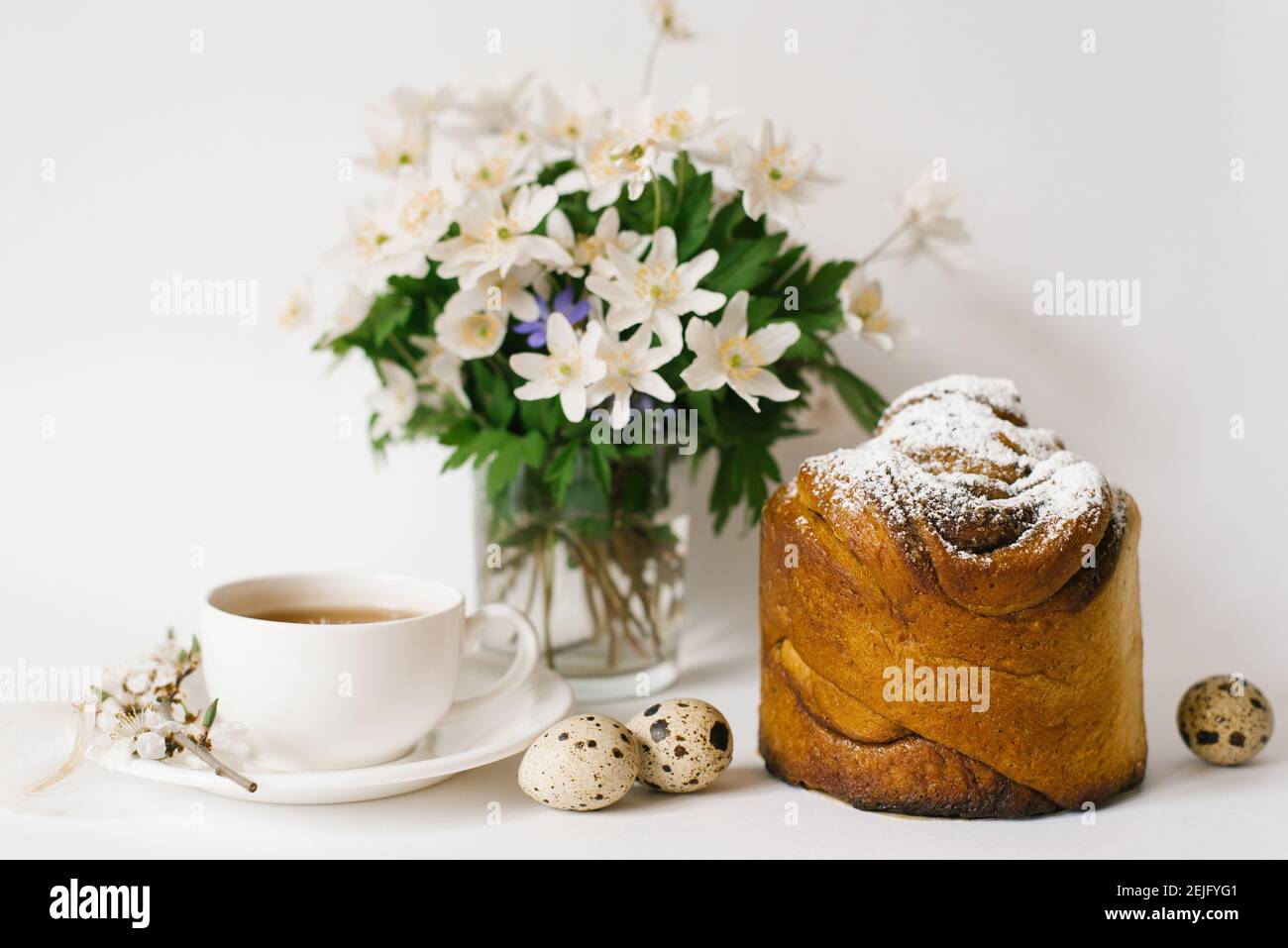 Easter card. A cake, a cup of tea, primroses in a vase and quail eggs on a light background Stock Photo