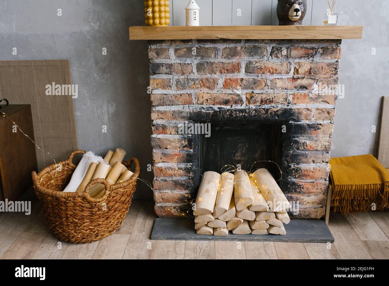 Scandinavian interior with red brick fireplace, wicker basket for firewood, pile of logs for a fire Stock Photo