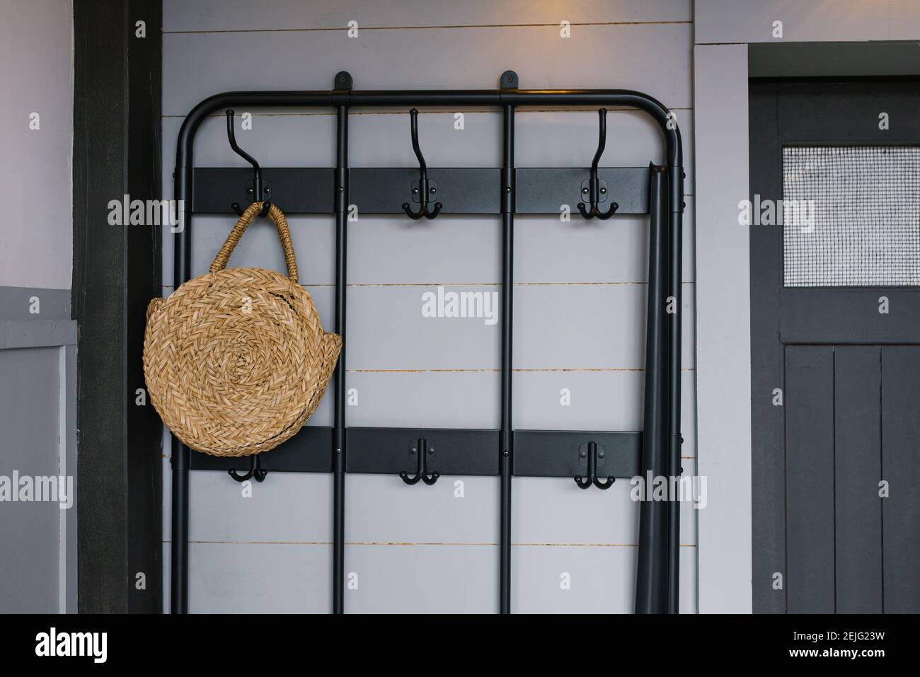 A wicker bag hangs on a hanger near the front door in the interior of a Scandinavian house Stock Photo