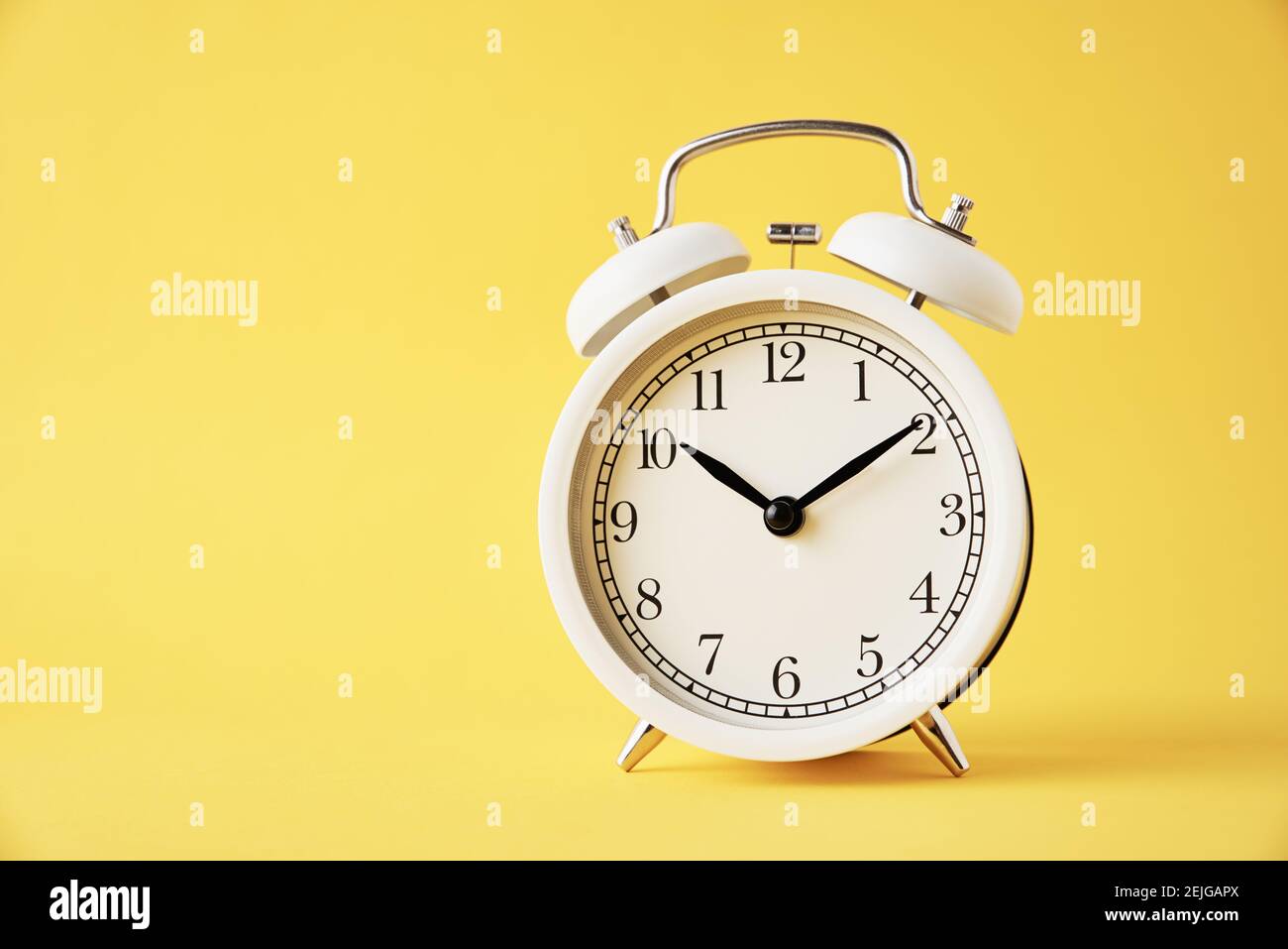White vintage alarm clock on yellow background with copy space Stock ...