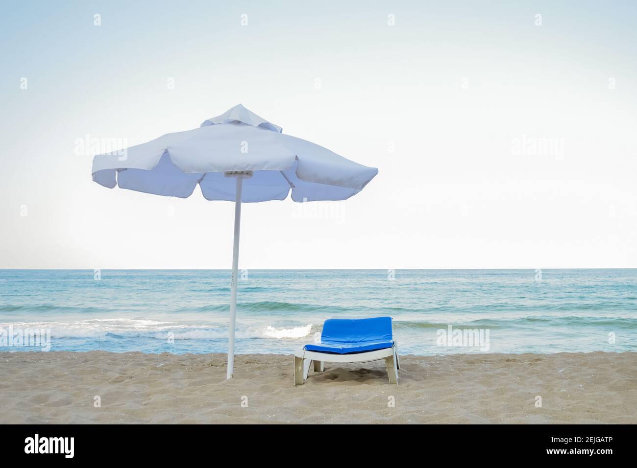 Beach chair and umbrella without people during the crisis of the tourism industry. The concept of the spread of coronavirus on the planet. Stock Photo