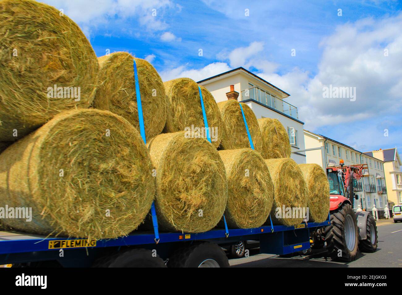 A tractor loaded with bales of hay passes along the coastal street of