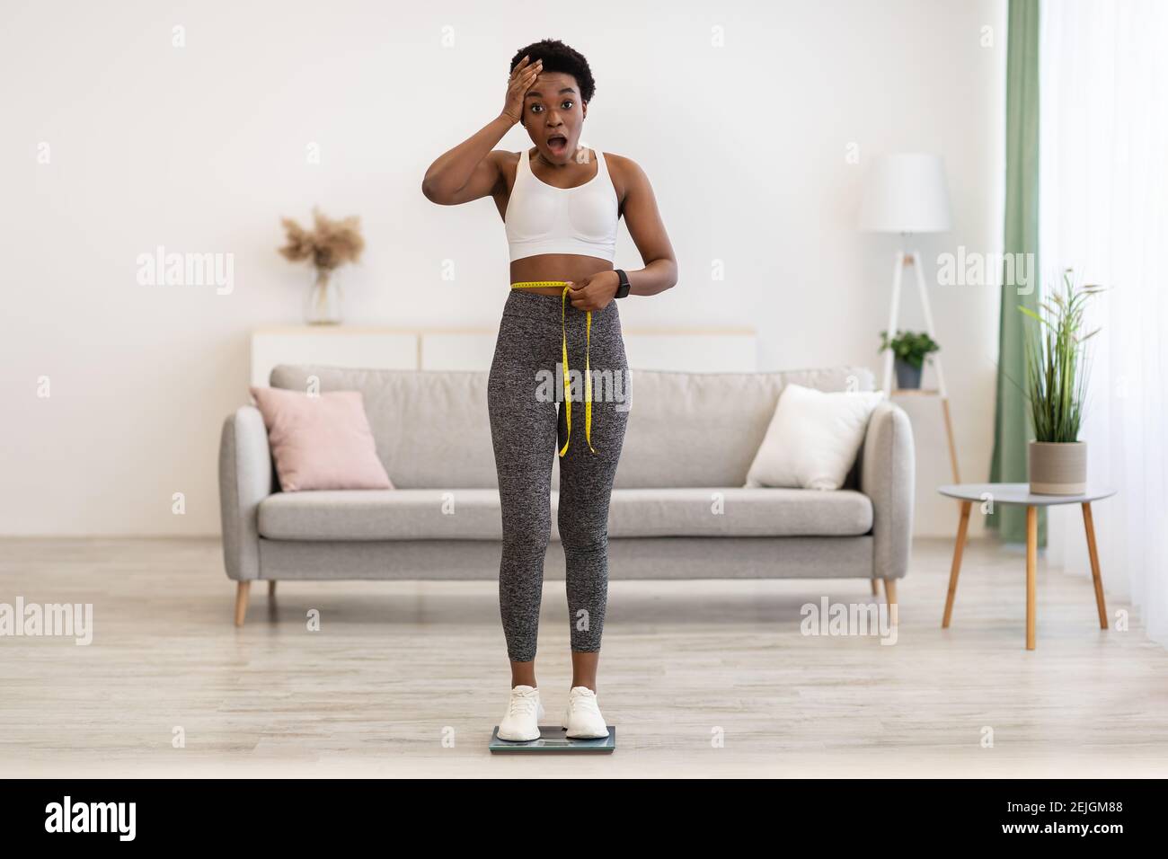 African Lady Weighing After Weight Gain And Measuring Waist Indoors Stock Photo