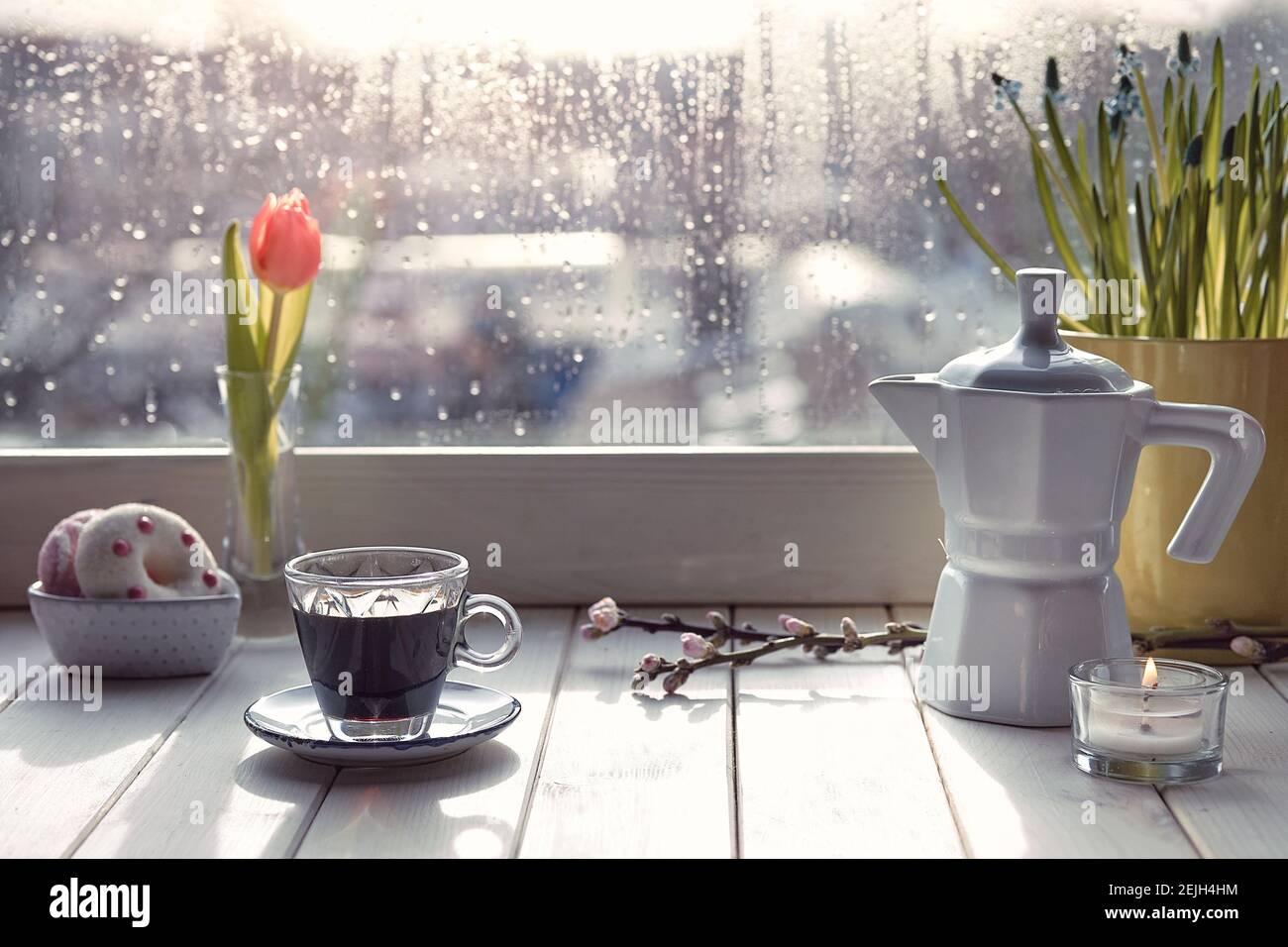 Oriental coffee in traditional Turkish copper coffee pot with flowers on window sill. Wooden windowsill with orange tulips and hyacinth flower pot Stock Photo