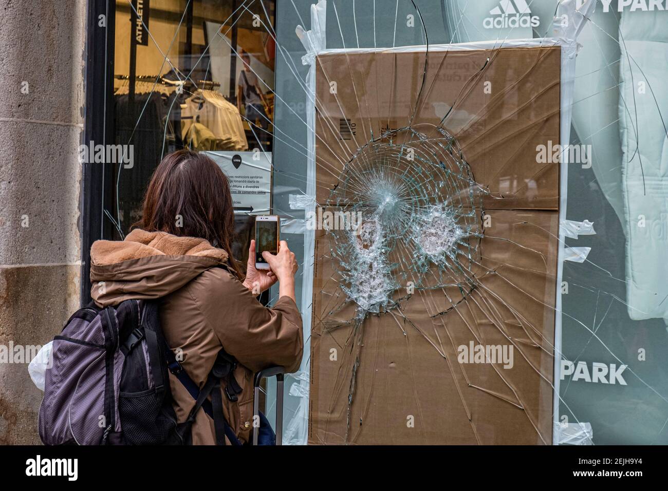 A person is seen taking photos of the damage on Adidas store window in  Passeig de Gràcia.More than 50 stores have suffered damage to their shop  windows and some have been looted