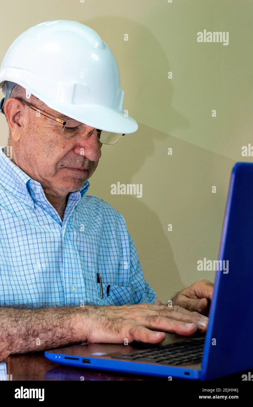Civil engineer wearing a helmet and working on a laptop Stock Photo