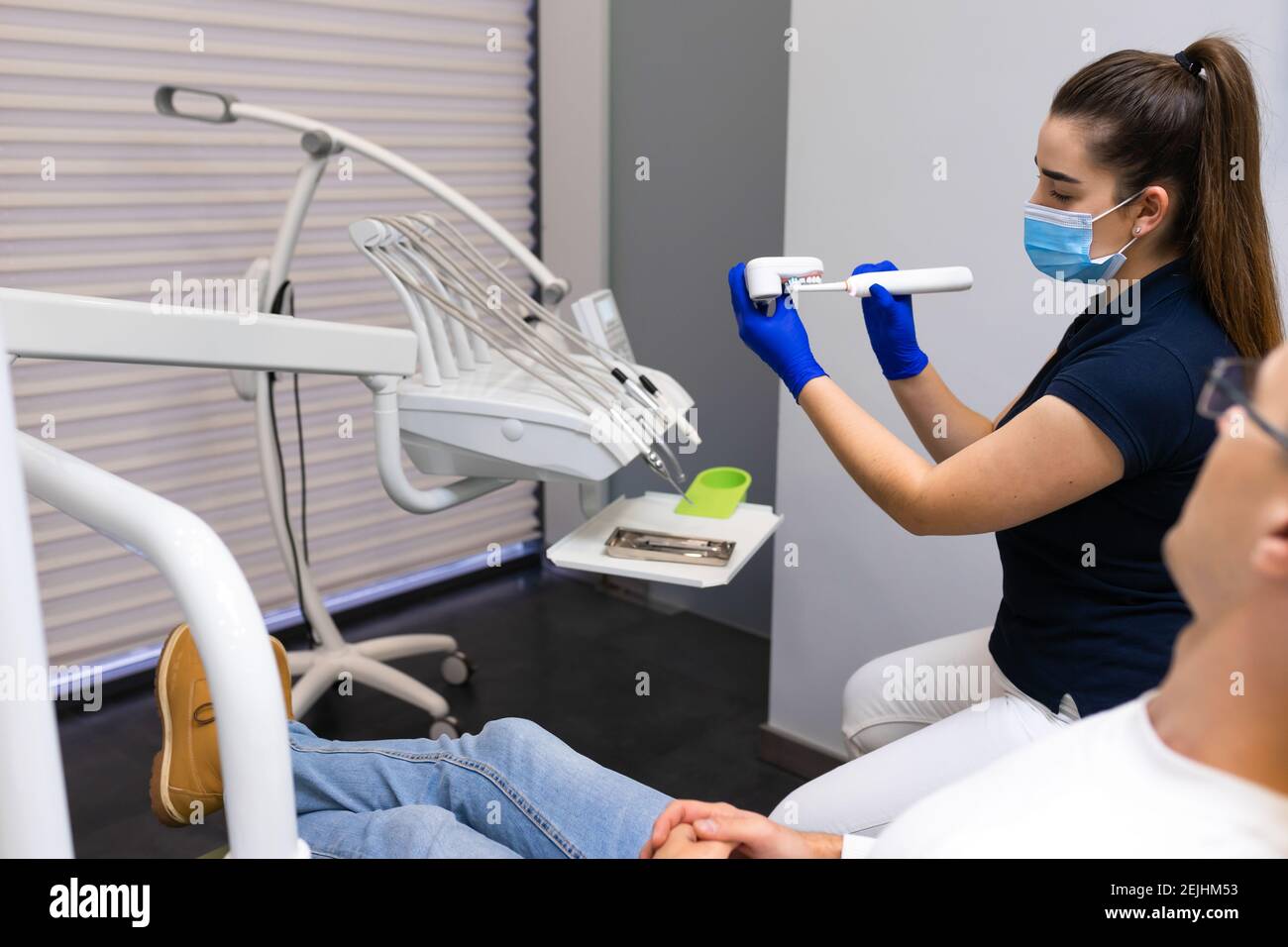 Dentist hygienist using the example of artificial jaw shows how to