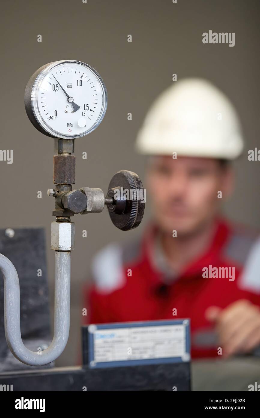 Thermometer on the hot water supply pipe, heating system. Technician wearing red jacket with