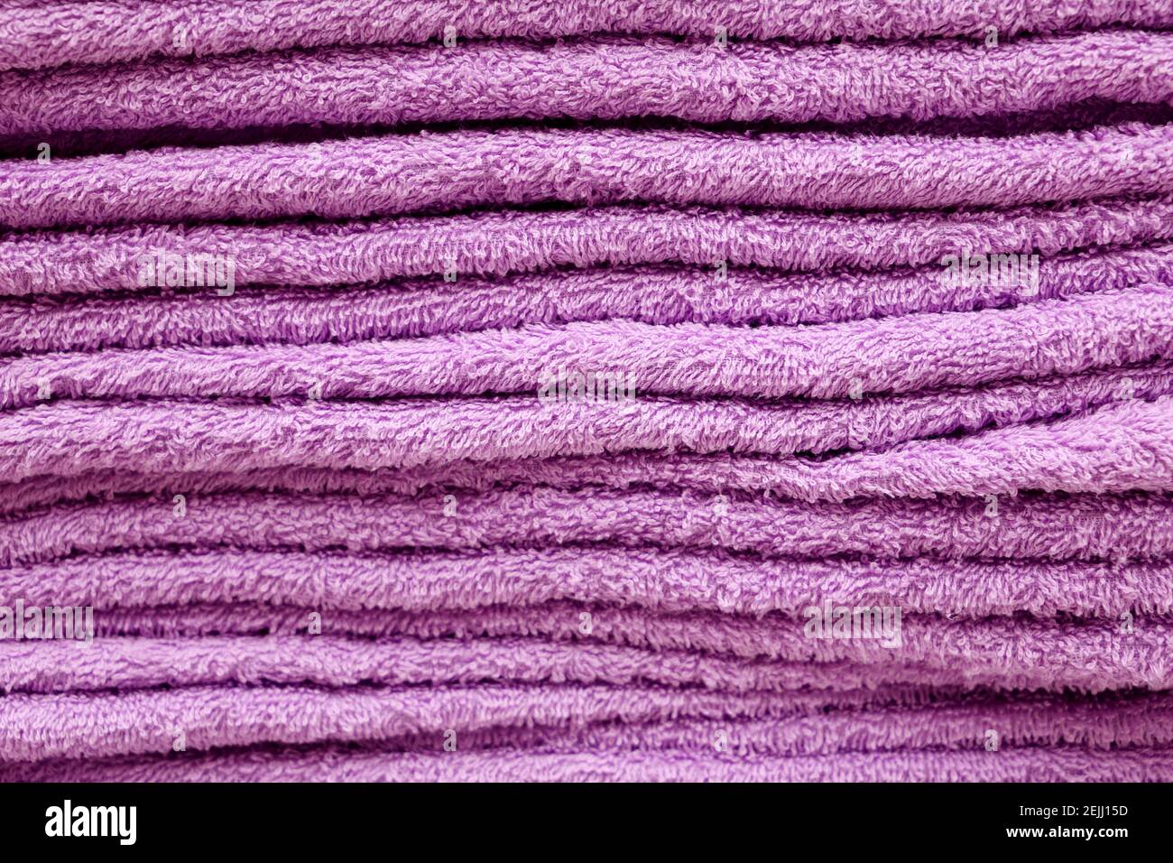 Stack of terry towels, selective focus. Soft background, purple bath textile close up Stock Photo