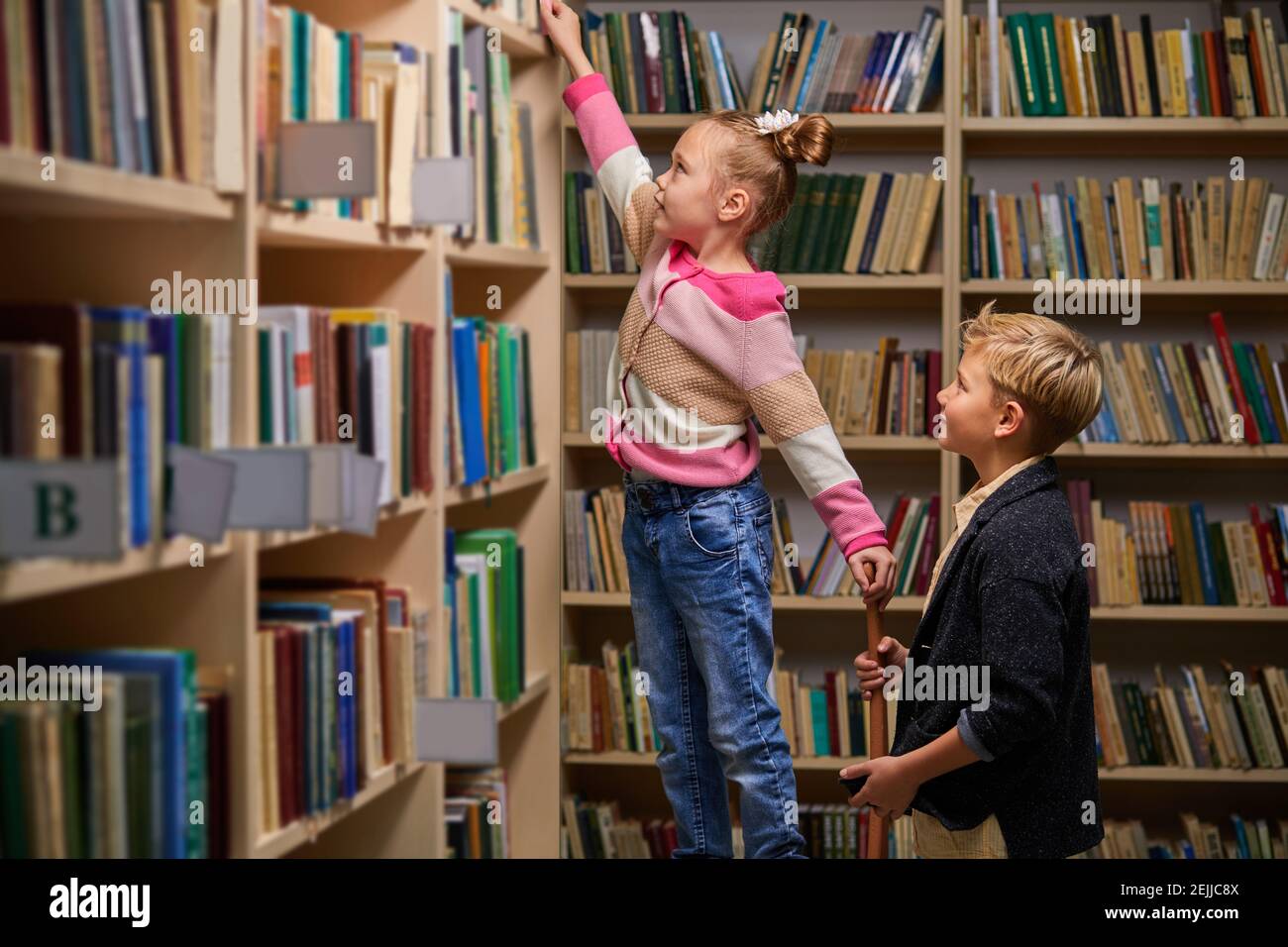 brother and sister choose books in library, having conversation, in library of school Stock Photo