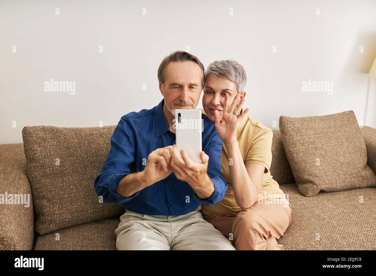 Senior couple making video call while sitting on a sofa Stock Photo