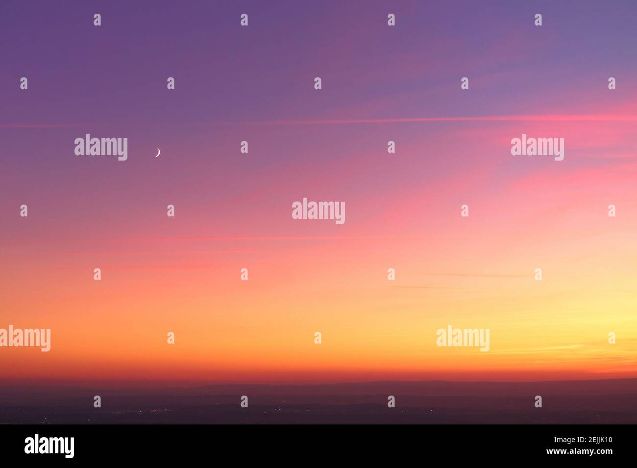 Evening colorful purple-pink sky with red clouds and orange horizon, crescent moon. Aerial photography, orange sky over the whole photo. Stock Photo