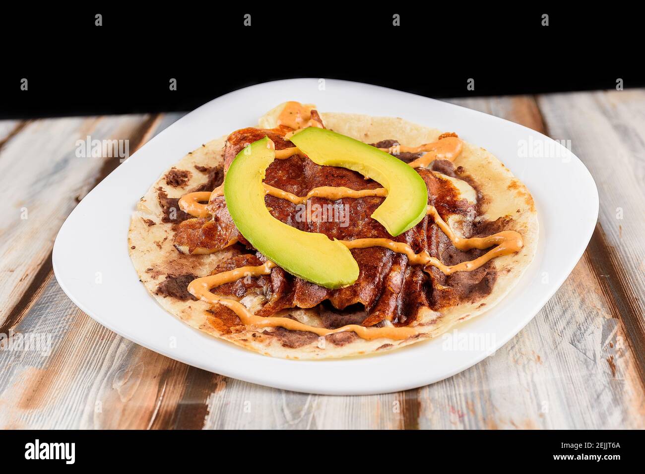 Closeup to a Mexican taco dish with meat with cheese and avocado on a restaurant table Stock Photo