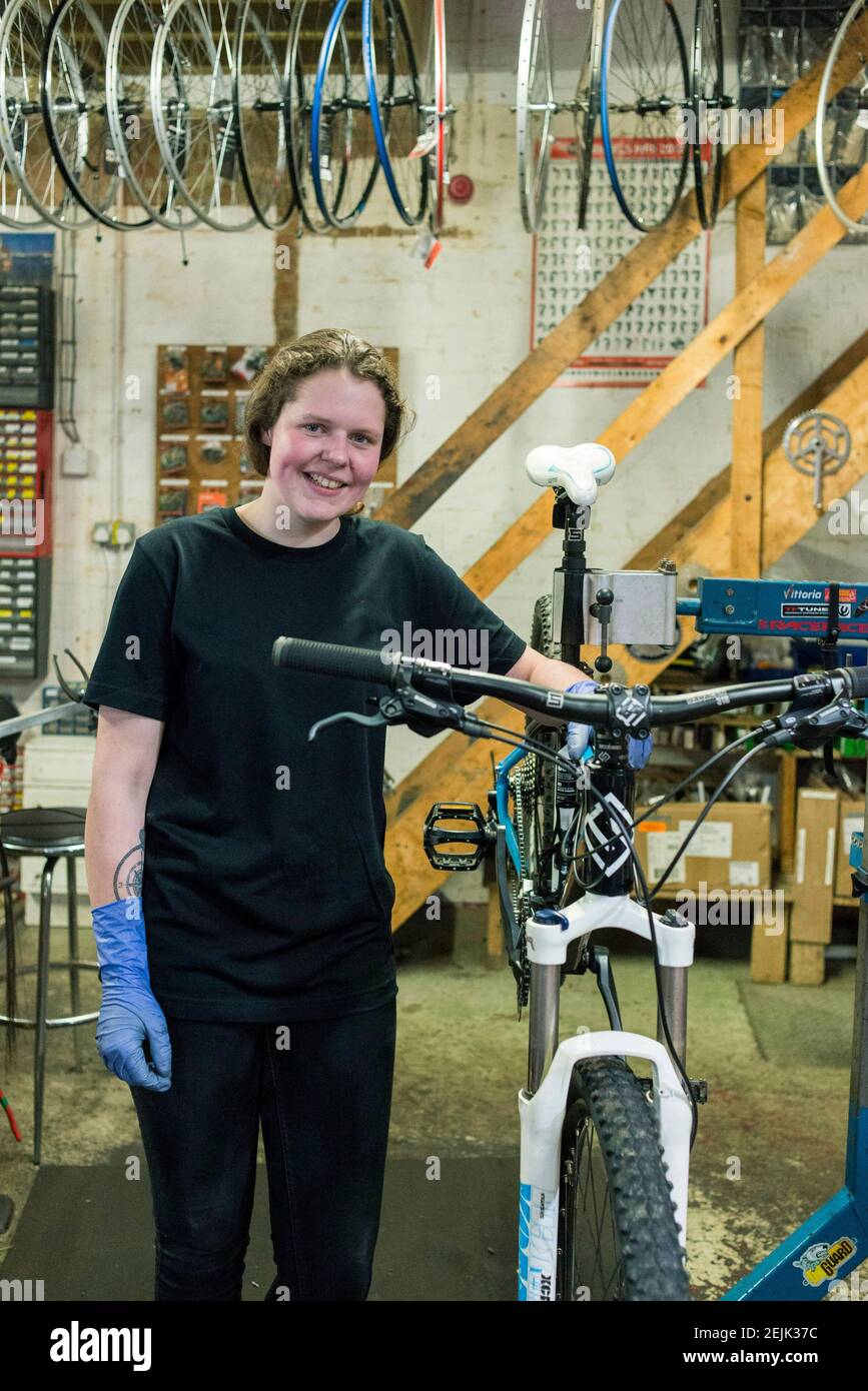 A female bike mechanic stands at her work stand in a cycle servicing / repair Stock
