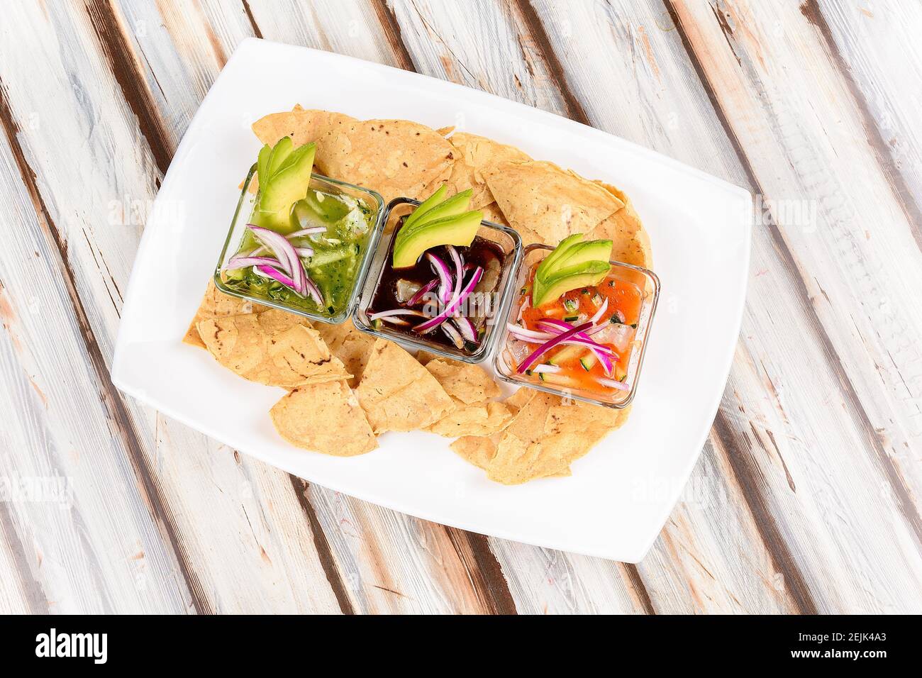 Plate with ceviches prepared with different sauces accompanied with tortillas or avocado Stock Photo