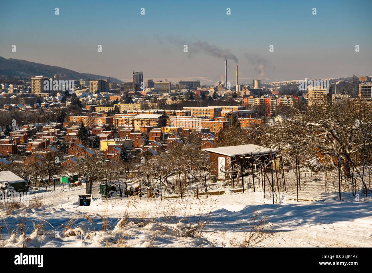 Snowy outskirts and downtown view of city Zlin with typical red brick houses and heating plant chimney on background. Czech republic. Stock Photo