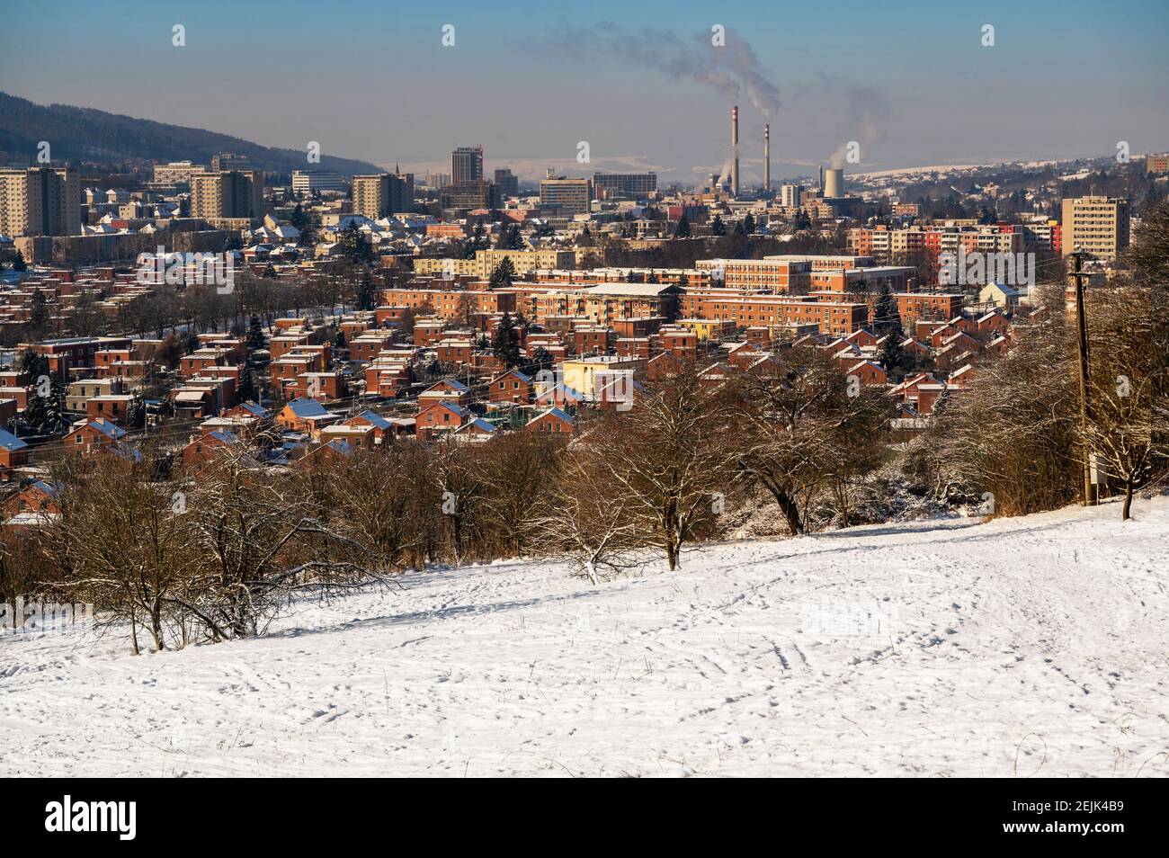 Snowy winter view of northeastern part of city Zlin with typical red brick houses in residential area and heating plant chimney on background, Czechia Stock Photo