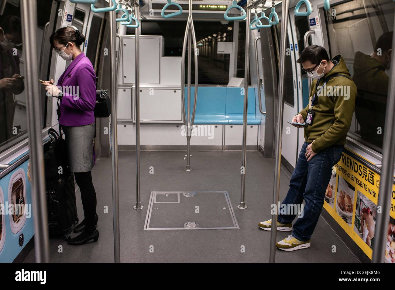 Airline staff and a passenger wear surgical masks inside an empty train
