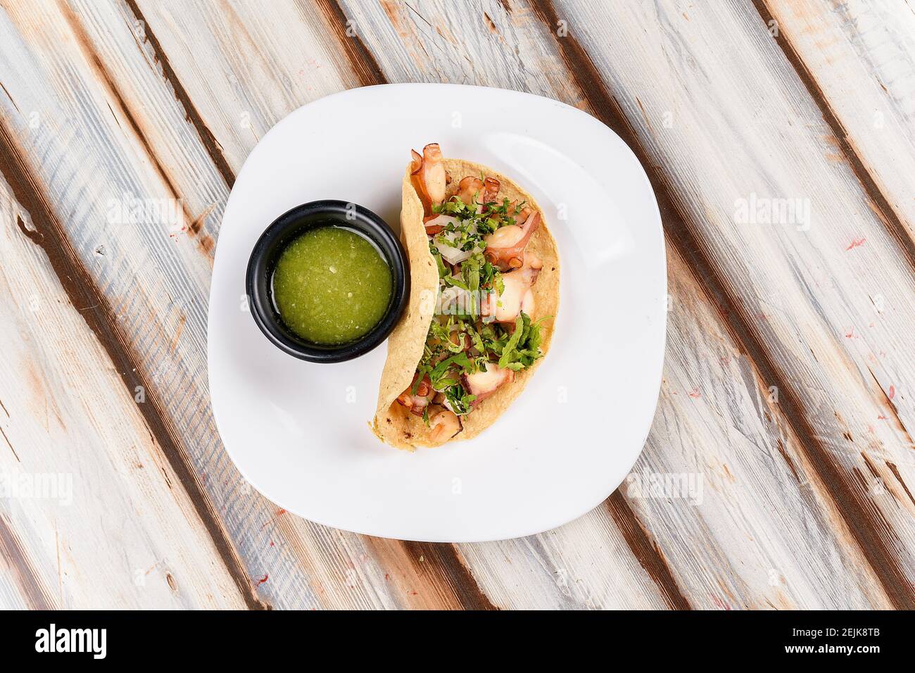 Dish with an octopus taco with coriander and green tomato sauce Stock Photo