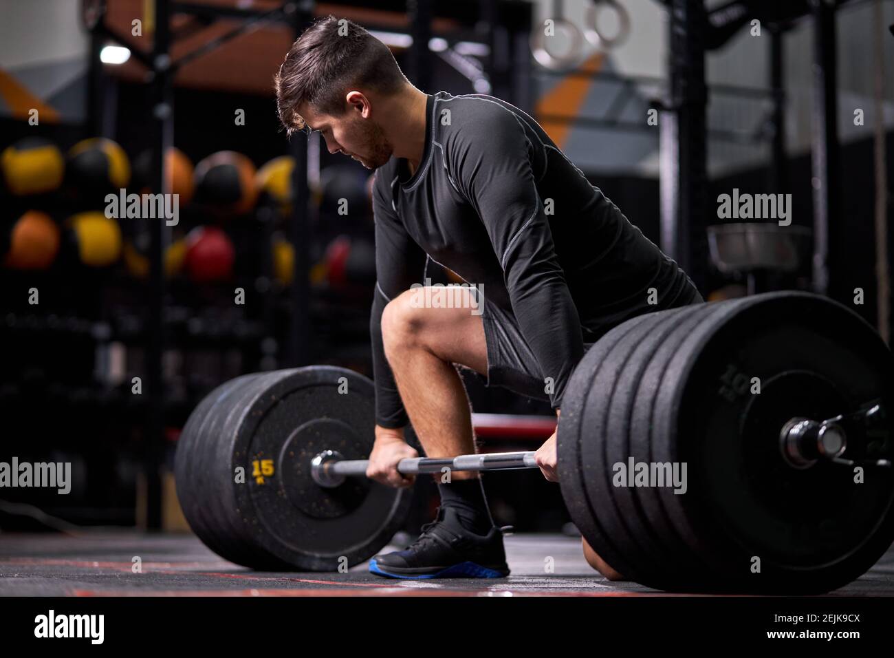 Athlete standing on his knee preparing to make deadlift at gym, young  caucasian man in black sportswear engaged in bodybuilding, concentrated on  weigh Stock Photo - Alamy