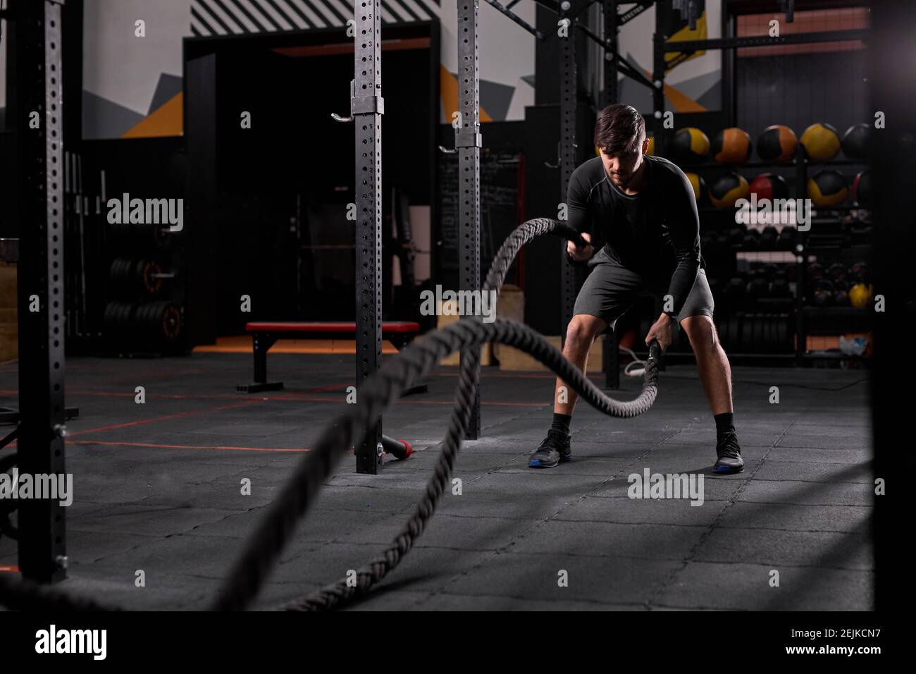 Athlete doing battle ropes exercise at cross fit gym. motivation sport ...
