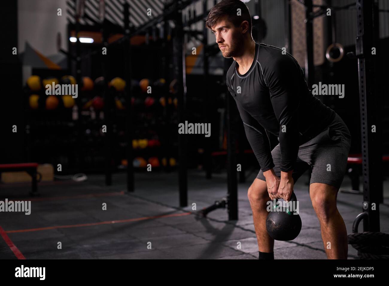 man with big muscles holding heavy kettlebell for cross fit swing