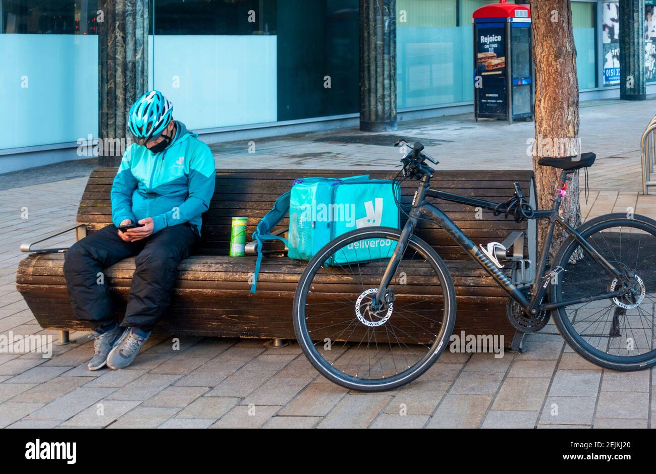Deliveroo bike delivery man checking his cell phone for orders in Liverpool Stock Photo