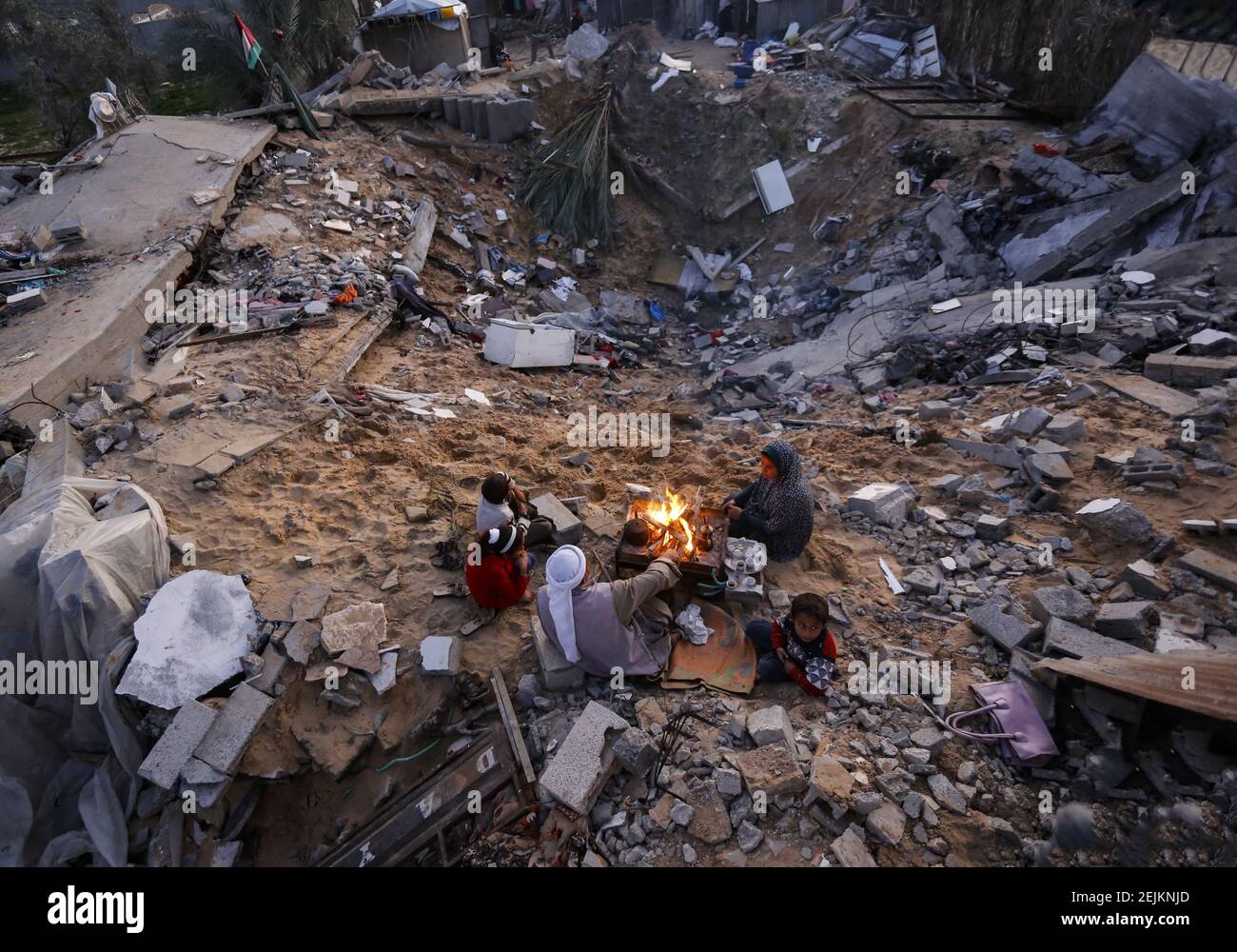 A Palestinian family sit around the fire to warm themselves outside ...