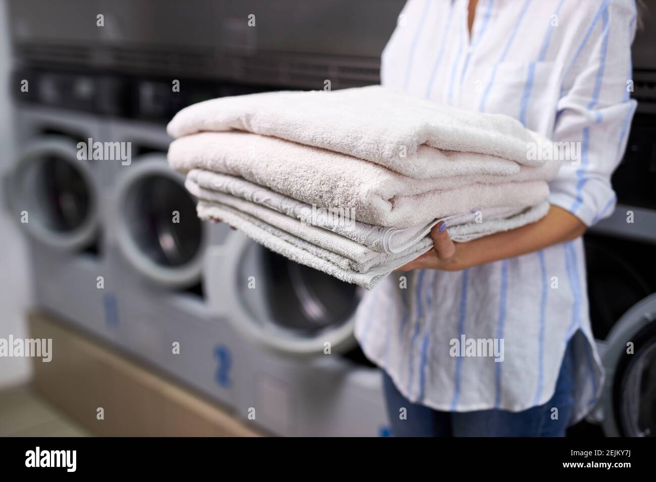 cropped woman is holding a stack of white towels. female in washing house. concept of service in hotels, laundry, spa Stock Photo