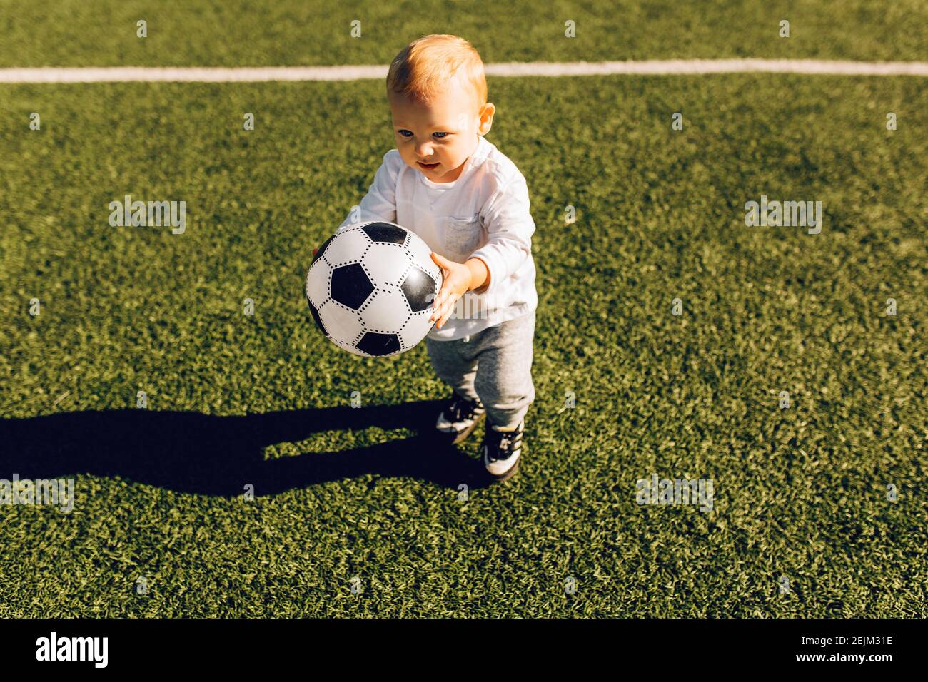 cute-little-boy-playing-soccer-with-ball-outdoors-on-soccer-field-stock