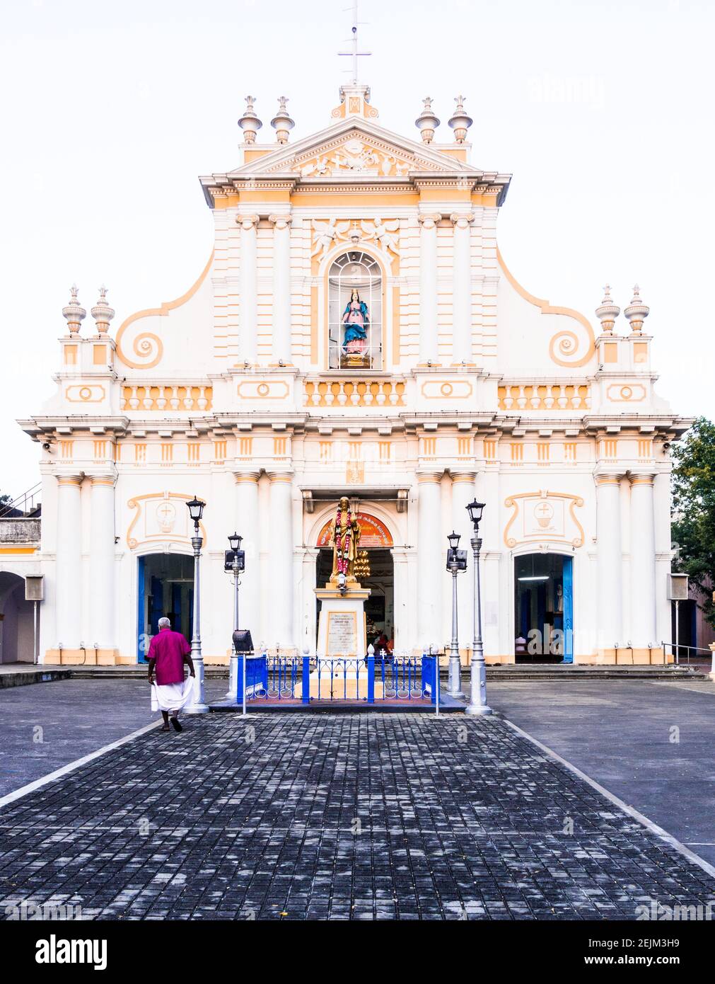 Immaculate Conception Cathedral, Portuguese-style church with white & yellow columns & a gold statue, offering bilingual services. Stock Photo