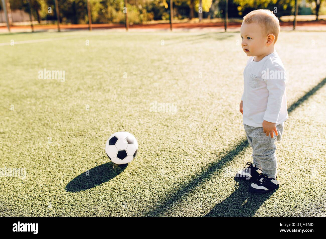 cute-little-boy-playing-soccer-with-ball-outdoors-on-soccer-field-stock