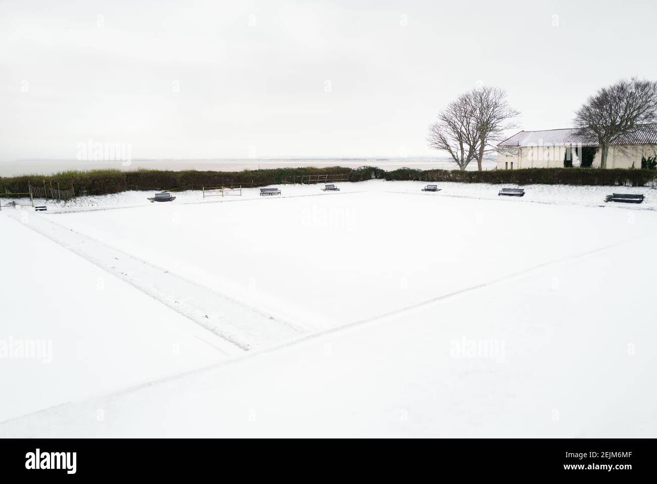 Benches around an outdoor bowling green out of season and covered in snow. Stock Photo