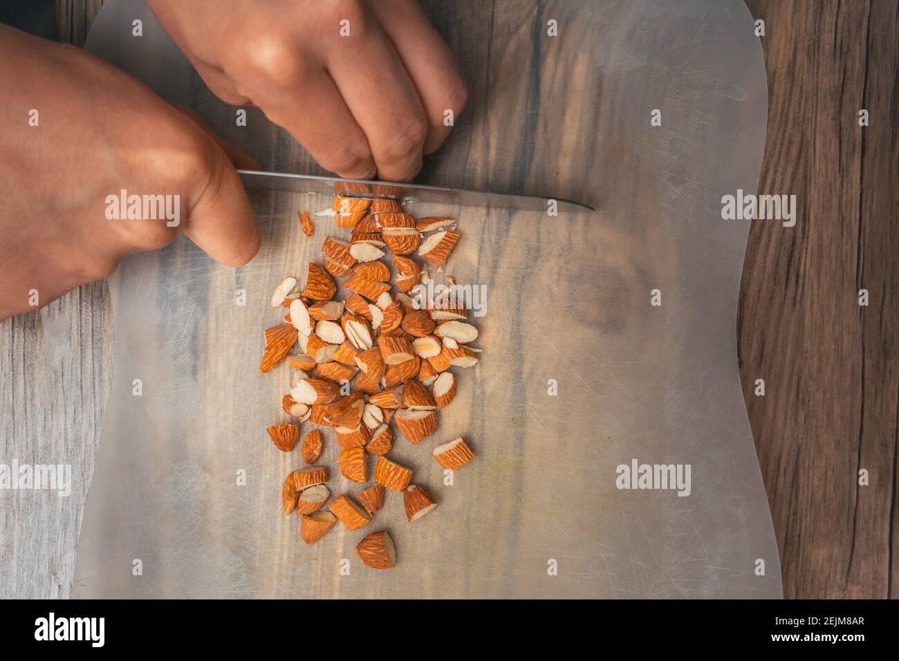 Close-up of a person with kitchen knife cutting almonds in his kitchen Stock Photo