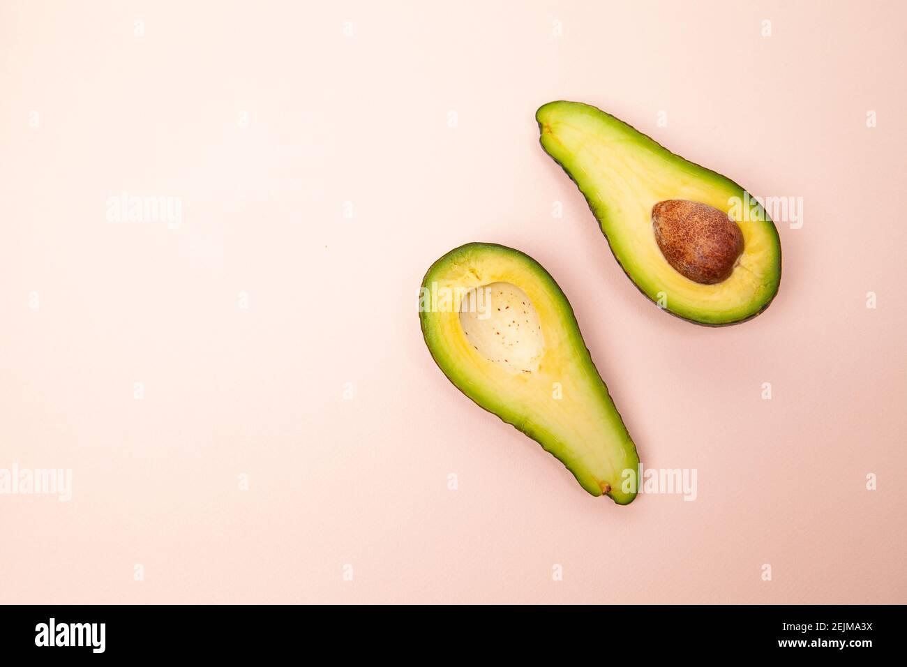 Halved and whole avocados on pink table Stock Photo - Alamy