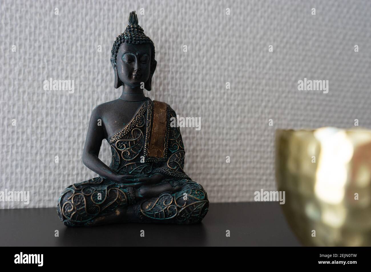 Buddha statue inside house in front of a white wall Stock Photo - Alamy