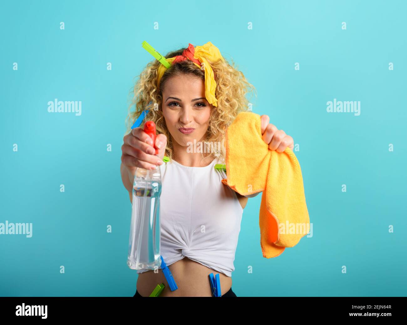 Blonde housewife splashs disinfectant to remove viruses and bacteria. Cyan background Stock Photo