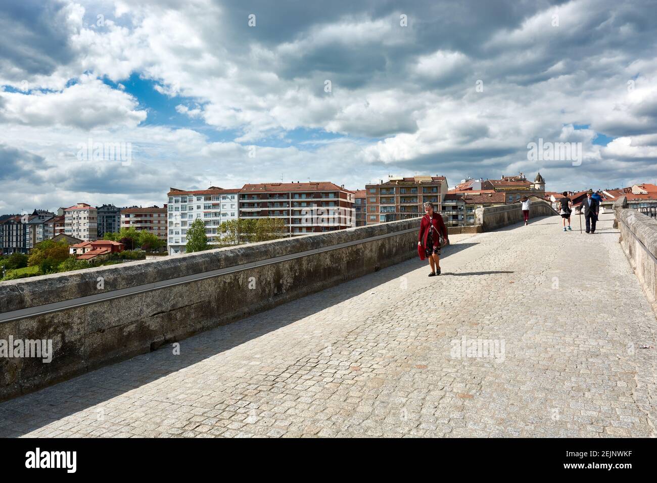 APRIL 27, 2018 - OURENSE, GALICIA, SPAIN: View of the street on the famous Roman Bridge of Ourense with people walking, the city behind and a cloudy b Stock Photo