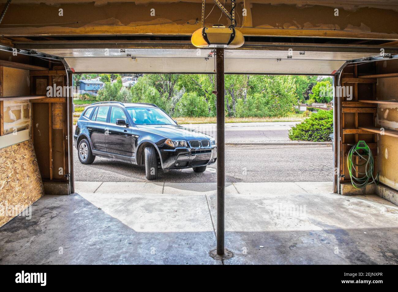 Black Suv turning into garage with automatic overhead door opener