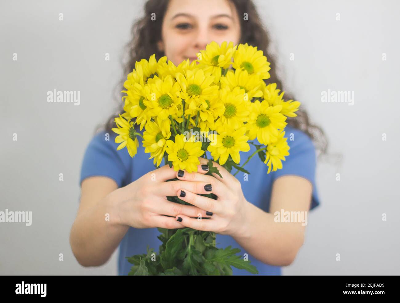 brunette woman in blue sweater holding yellow flowers Stock Photo